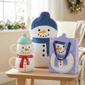 Snowman Snuggles gift set with two stacked snowman mugs, blue-hatted bouclé cushion and lavender snowman gift bag.