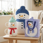 Snowman Snuggles gift set with two stacked snowman mugs, blue-hatted bouclé cushion and lavender snowman gift bag.