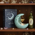 Moonlit Magic Gift Set featuring Blue Moon book storage box, pastel crescent moon oil burner and Moonlight Fairy glass potion bottle styled on a dark wooden bookshelf